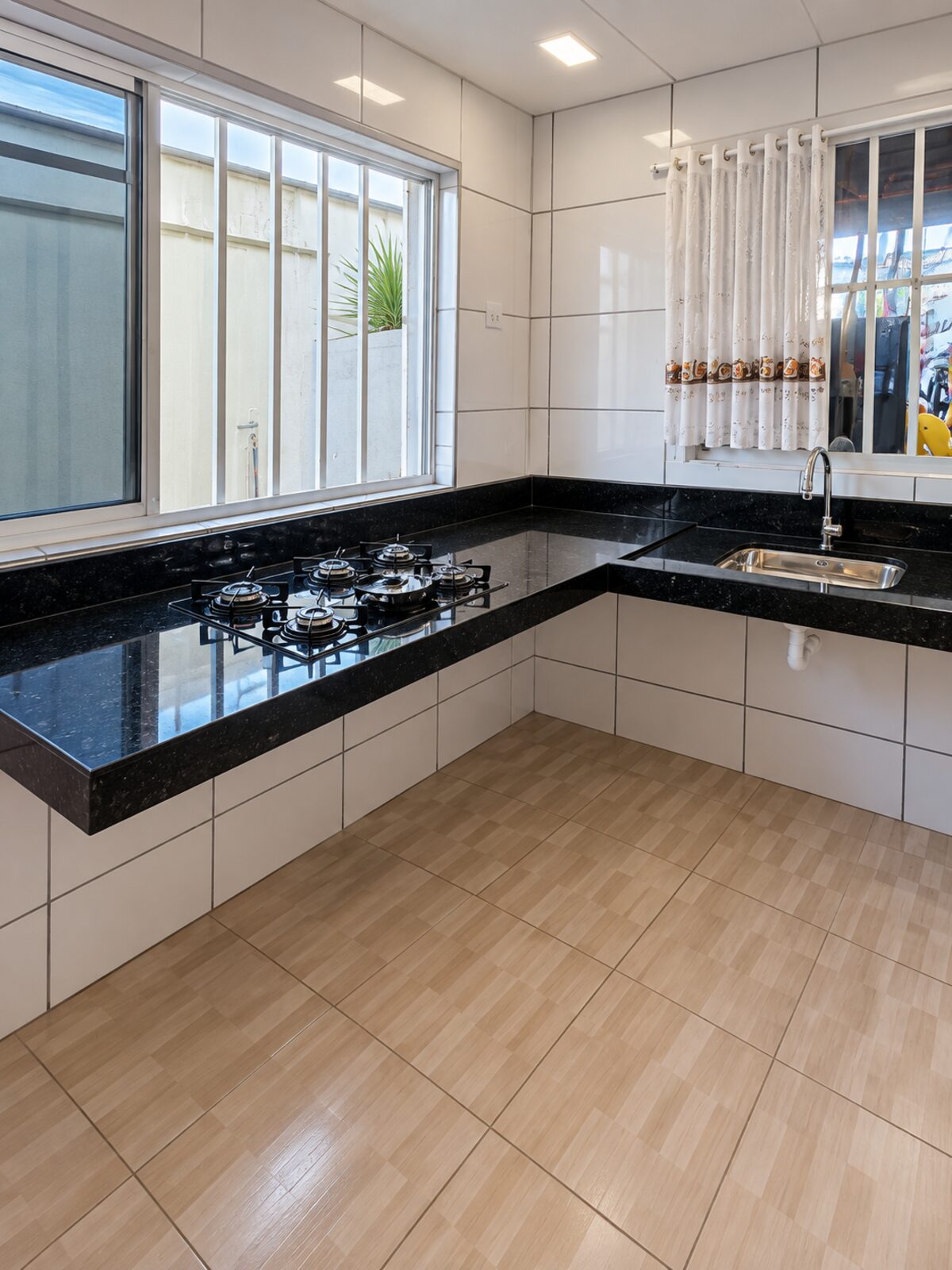 Balcão de cozinha planejado em granito preto com recorte para cooktop e cuba inox